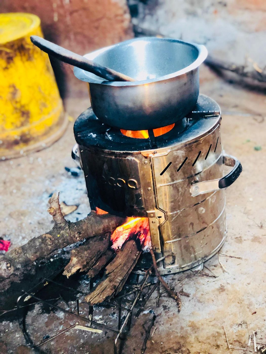 Metal cookstove in use with a pot over a wood fire.